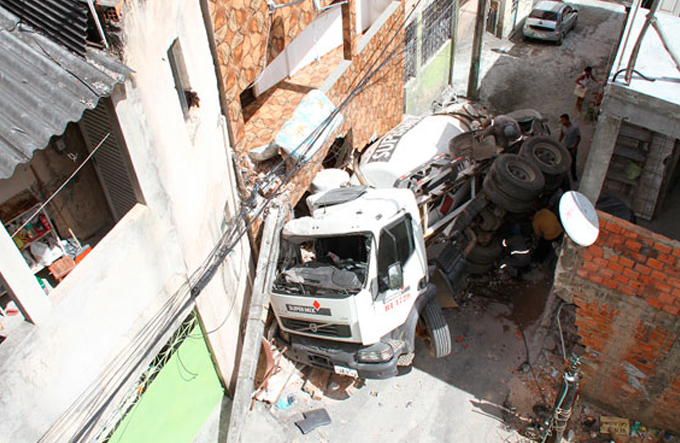 Caminhão betoneira tomba e danifica duas casas e um carro